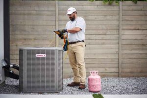 Dominion Service Company technician performing AC maintenance on outdoor unit