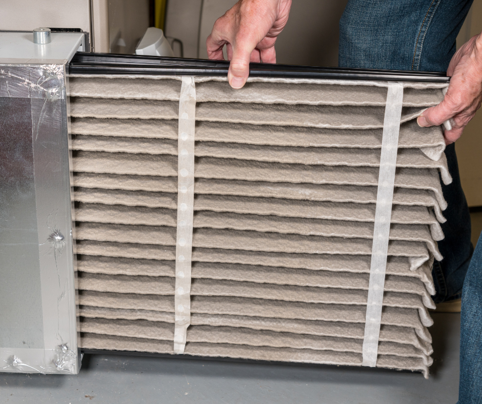 A person removes a dirty air filter from an HVAC unit