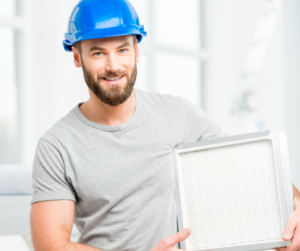 man in a blue hard hat holding a HEPA air filter