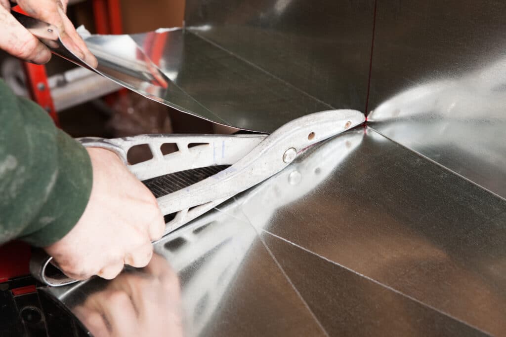 HVAC technician cutting sheet metal, raw materials for heating and cooling